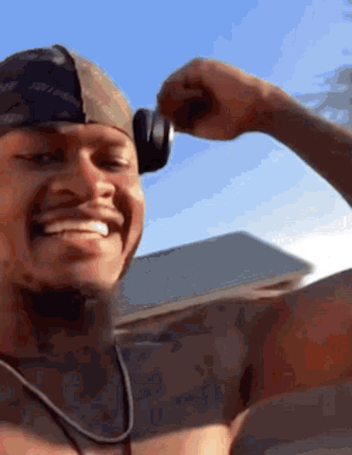 a shirtless man is wearing headphones and smiling .