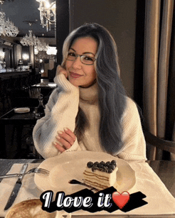 a woman is sitting at a table with a plate of food and the words " i love it " on the bottom