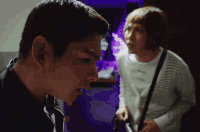 a man and woman are standing next to each other in a dark room