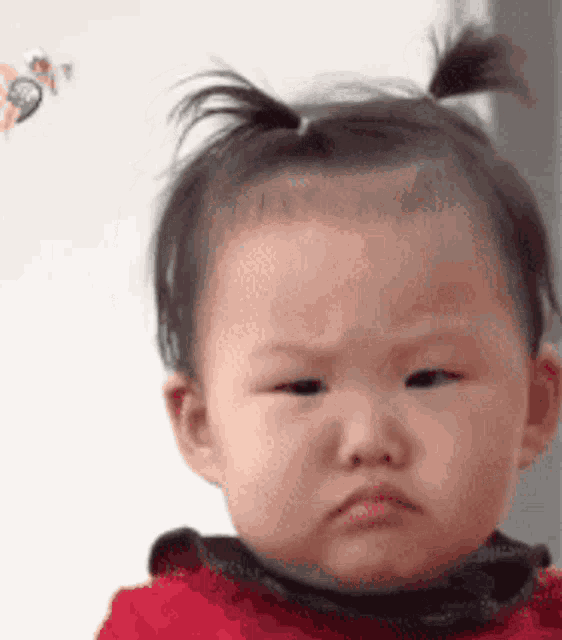 a baby with a ponytail is making a funny face and looking at the camera .