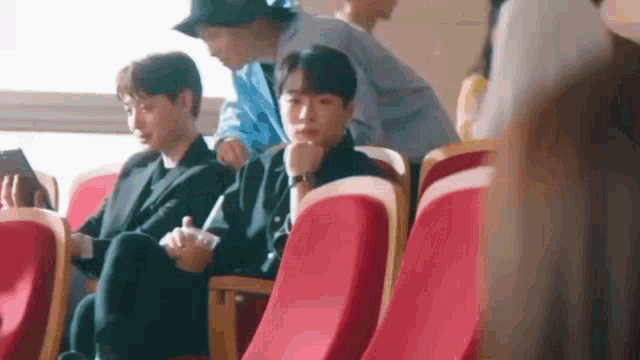 a group of people are sitting in red seats in a theater .