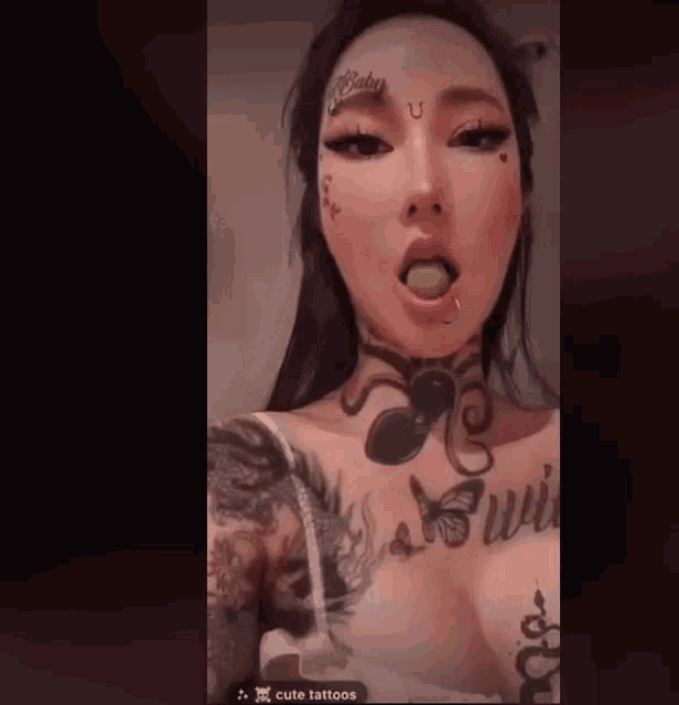 a woman with a lot of tattoos on her body has a green apple in her mouth