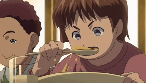 a boy is eating something with a spoon while another boy watches