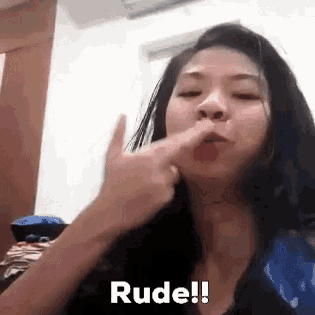 a woman is blowing her nose and making a rude gesture .