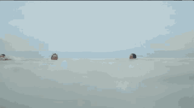 a group of people are swimming in the ocean and one of them is waving
