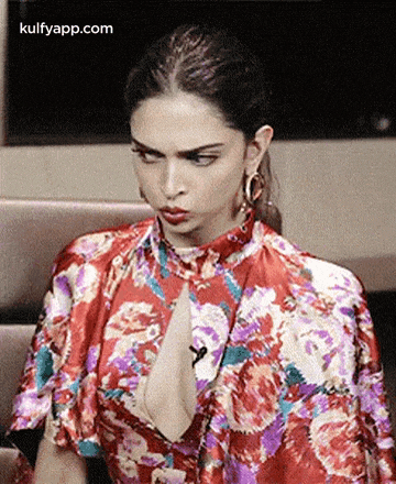a woman in a red floral dress is sitting on a couch .