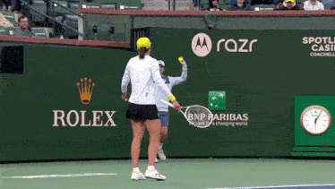 a tennis player is holding a tennis racquet in front of a rolex sign