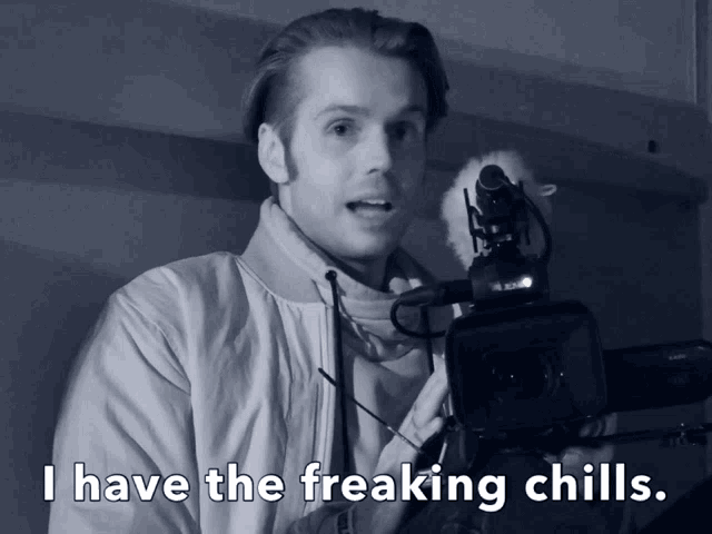 a black and white photo of a man holding a camera with the caption " i have the freaking chills "