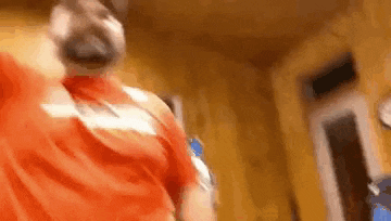 a man with a beard is wearing a red shirt and smoking a cigarette .