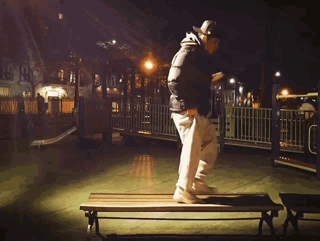 a person is jumping over a bench in a park