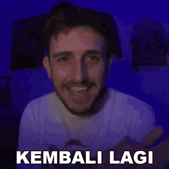 a man with a beard is smiling and pointing at the camera with the words kembali lagi written on the bottom .