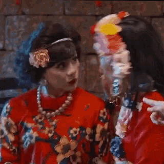 two women are laughing and one has a flower headband on