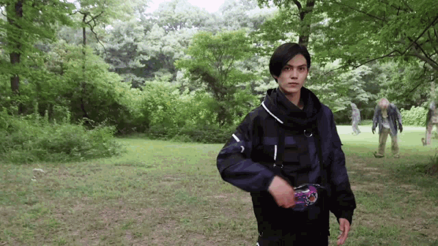 a man in a black jacket is standing in a park