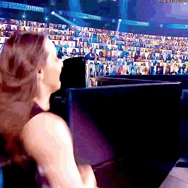 a woman sitting in front of a crowd with a sign that says smackdown on it