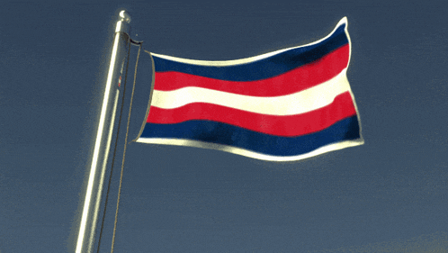 a red white and blue flag is waving in the wind against a blue sky
