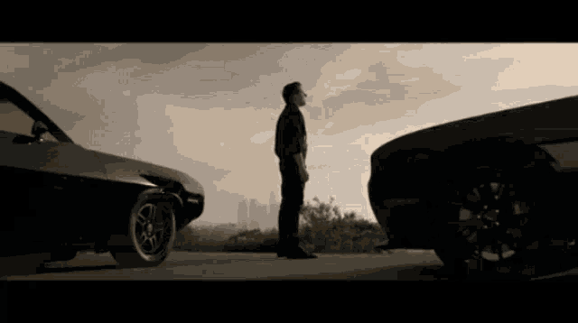 a man is standing in front of a car with a city in the background