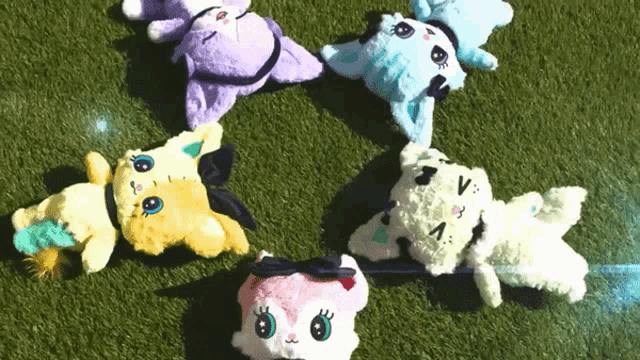 a bunch of stuffed animals are laying on the grass one of which has the letter v on it