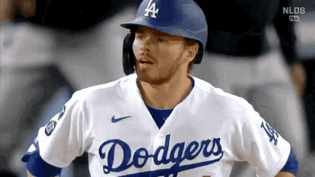 a baseball player for the dodgers is wearing a helmet and a white jersey .