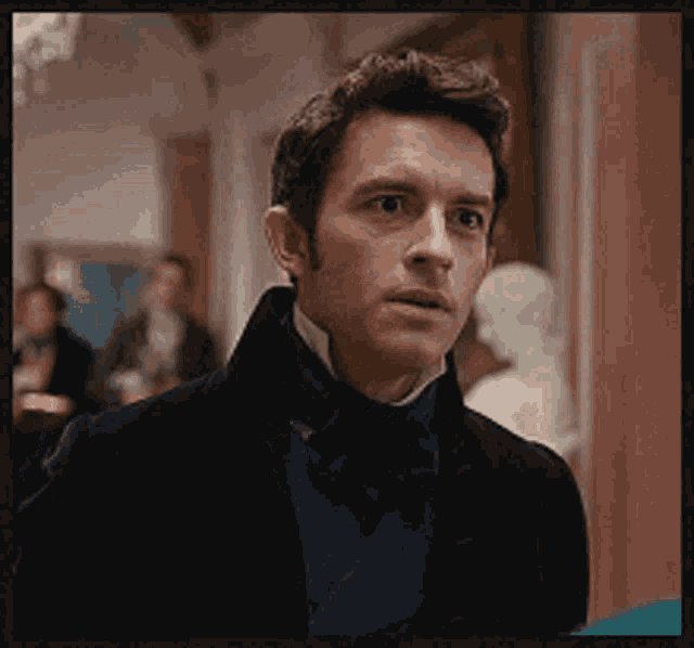 a man in a suit and bow tie is standing in a room with a statue in the background .