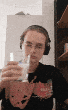 a young man wearing headphones is holding a glass of milk in his hand