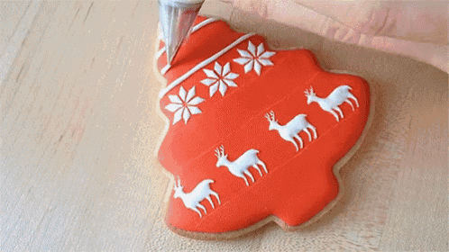 a person is decorating a christmas tree shaped cookie with snowflakes and deer