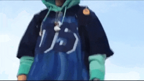 a person wearing a blue shirt and a hoodie is standing in front of a blue sky .