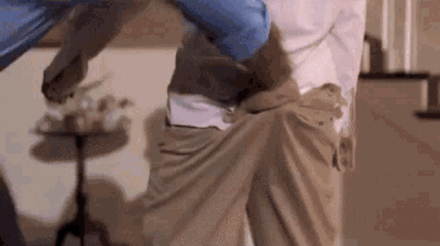 a man in a pink shirt is holding another man 's pants up .
