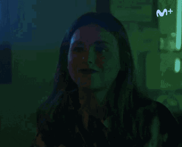 a woman is standing in front of a man in a dark room with green lights behind her .