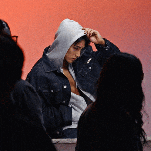 a man wearing a denim jacket with a hood on his head