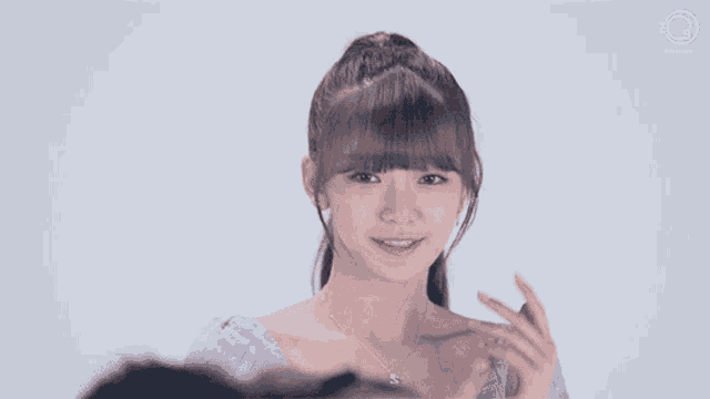 a young girl in a purple dress is smiling and pointing to her chest .