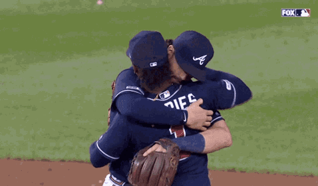 a couple of baseball players hugging each other with the fox logo behind them