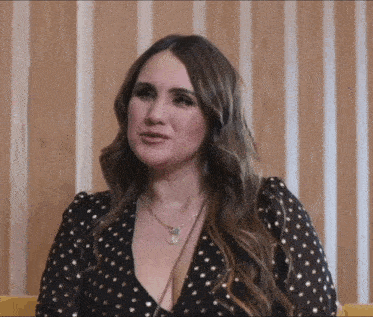a woman wearing a black and gold polka dot dress and a necklace with the letter j on it