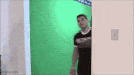 a man in a black shirt is standing in front of a green screen