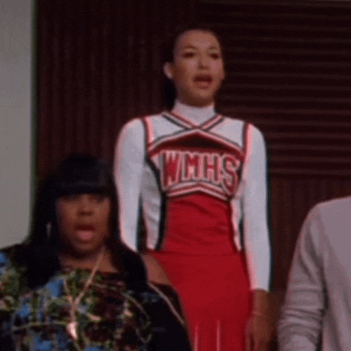 a cheerleader wearing a wmhs uniform is standing in front of a group of people