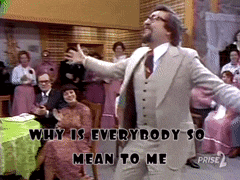 a man in a suit is dancing in front of a crowd with the words " why is everybody so mean to me " above him