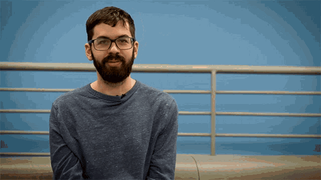 a man with glasses and a beard is sitting on a bench