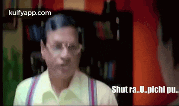 a man in a yellow shirt and suspenders is talking to another man in a room .
