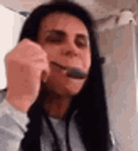 a woman is holding a spoon in her mouth and making a funny face .
