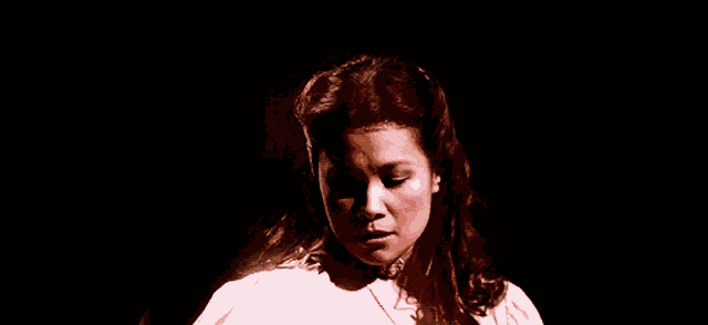 a woman in a white dress is standing in the dark