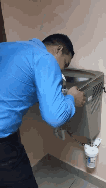 a man in a blue shirt is working on a machine