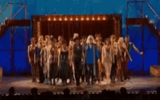 a large group of people are dancing on a stage .