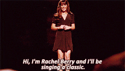 a woman in a black dress is singing a classic song
