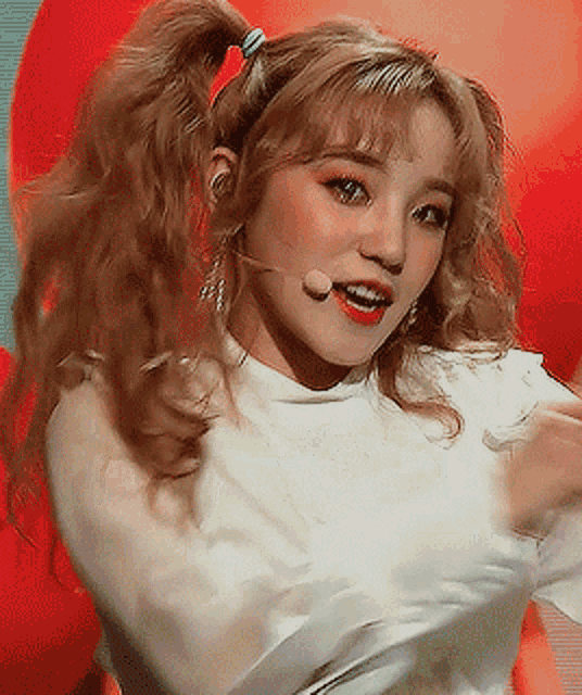 a woman with blonde hair is wearing a white shirt and a microphone .