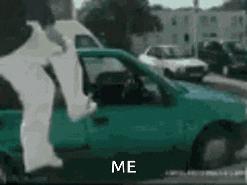 a person is standing in front of a green car with the words `` me '' written on the bottom .