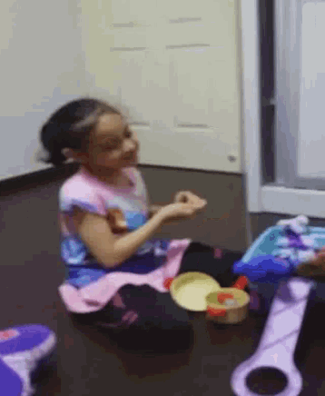 a little girl is sitting on the floor playing with a toy guitar