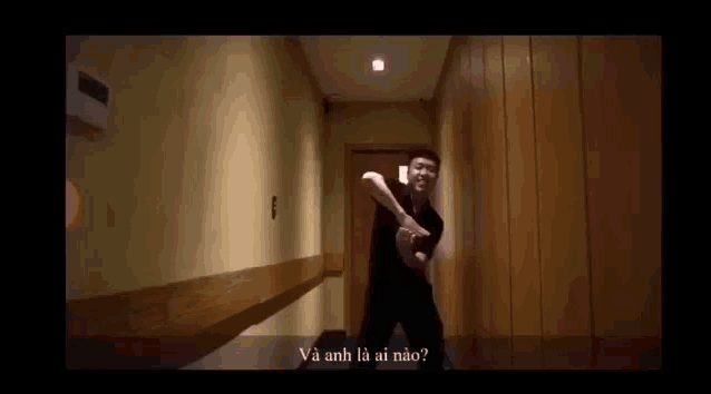 a man is dancing in a hallway with a wooden wall behind him .