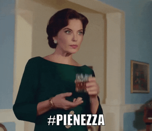 a woman in a green dress is holding a glass of whiskey and the caption #pienezza is above her