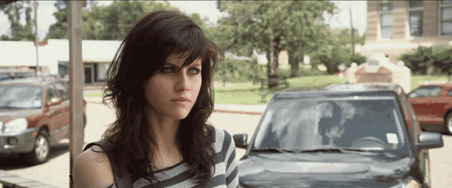 a woman is standing in front of a black car