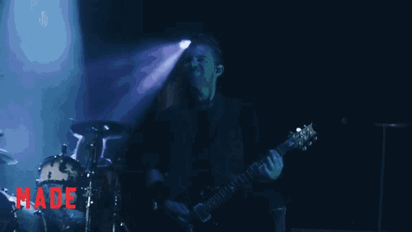 a man playing a guitar on stage with the words made for elevation below him