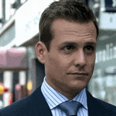 a man in a suit and tie is standing in front of a sign that says ' a ' on it